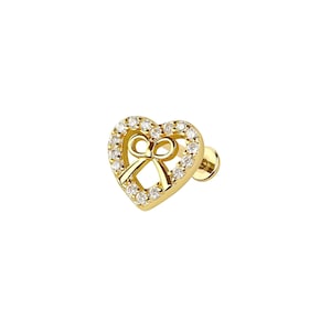 May include: A gold-coloured stud earring shaped like a heart, featuring a bow design at its centre. The heart is edged with small, clear gemstones. The earring includes a post and backing for secure wear.