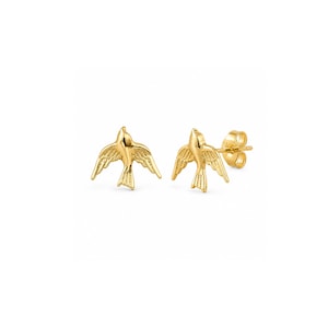 May include: A pair of gold stud earrings shaped like birds in flight with outstretched wings. The earrings feature a polished metallic finish and include standard post backs for secure attachment, showcasing a detailed avian silhouette design.