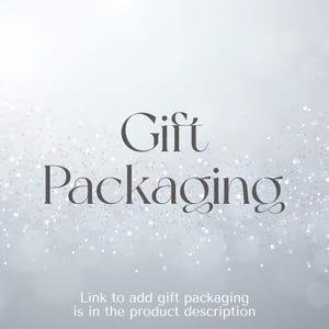 May include: A light gray background with a subtle white glitter effect and the dark gray text Gift Packaging centered in the middle. Below this, smaller text reads Link to add gift packaging is in the product description.