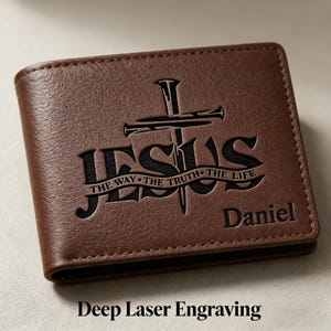 May include: Brown leather wallet with the word "JESUS" and a cross engraved on the front. The text "THE WAY THE TRUTH THE LIFE" is below the word "JESUS". The name "Daniel" is engraved below the text. The words "Deep Laser Engraving" are at the bottom.