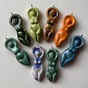 May include: Eight ceramic figurines of women in various poses, each with a different color glaze. The figurines are all about 3 inches tall and have a simple, elegant design.