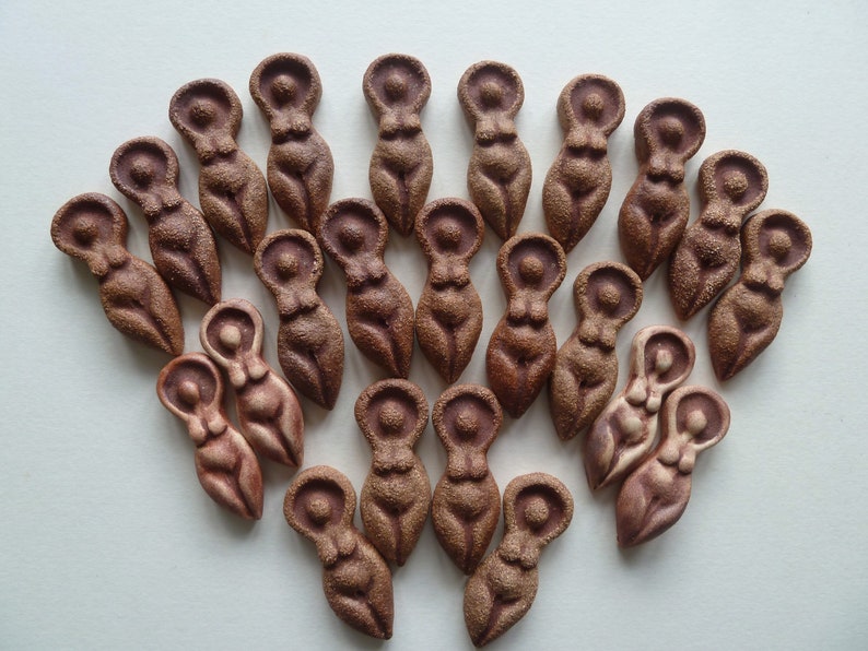 Puede incluir: Una colecci&oacute;n de 20 peque&ntilde;as figuritas de cer&aacute;mica marr&oacute;n con forma de mujer. Las figuritas est&aacute;n dispuestas en forma de abanico, con la parte superior del abanico apuntando hacia la parte superior de la imagen.
