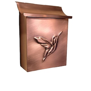 May include: A copper mailbox featuring a hummingbird design. The mailbox has a slightly curved top and a textured finish.
