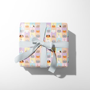 May include: A present wrapped in patterned paper with cartoon cat faces wearing party hats. The gift is tied with a pale blue ribbon and bow, suitable for a birthday or special occasion.