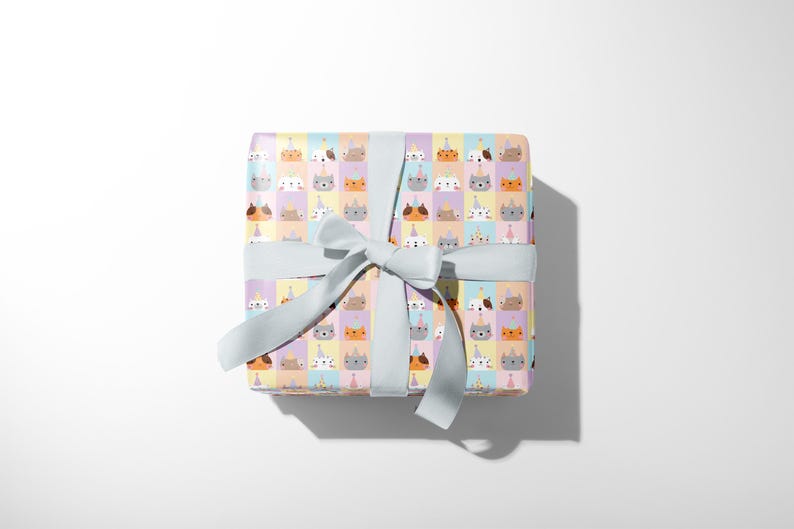 May include: A present wrapped in patterned paper with cartoon cat faces wearing party hats. The gift is tied with a pale blue ribbon and bow, suitable for a birthday or special occasion.