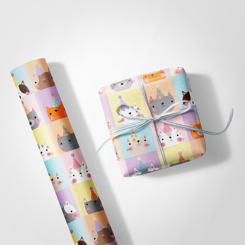 May include: A roll of gift wrap and a wrapped present, both decorated with a repeating pattern of cartoon cats wearing party hats. The cats are in various colours, set against pastel squares. The gift is tied with a light blue ribbon.