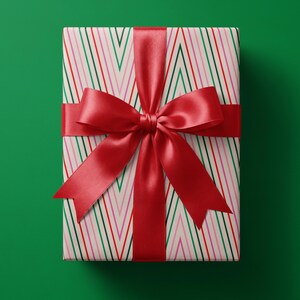 May include: A rectangular gift box wrapped in cream-colored paper featuring a repeating pattern of thin vertical chevron stripes in red, green, and pink. The package is tied with a wide, smooth, deep red satin ribbon finished in a large bow.