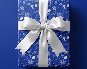 May include: A rectangular gift box wrapped in deep blue paper featuring a repeating white line-art pattern of snowmen, snowflakes, and holiday ornaments. The package is tied with a wide, smooth, white satin ribbon tied in a large center bow.