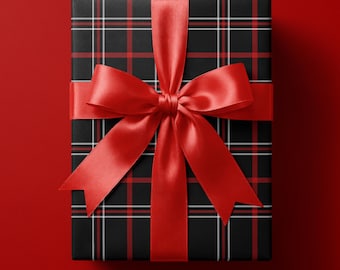 May include: A rectangular gift box wrapped in black paper featuring a red and white plaid pattern. The package is tied with a wide, smooth, vibrant red satin ribbon that is tied into a large, centered bow with two long, pointed tails.