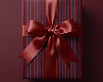 May include: A rectangular gift box wrapped in dark burgundy paper featuring thin vertical stripes in a darker shade. The package is tied with a wide, smooth, satin ribbon in a matching deep burgundy colour, tied into a large, centred bow.