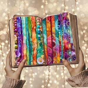 A person's hands holding an open book with colorful fabric and beads visible on the pages, set against a background of twinkling lights.
