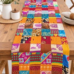 May include: A rectangular table runner featuring a vibrant patchwork design composed of various fabric squares. The textile displays a multitude of colors including red, orange, yellow, blue, and purple, with intricate floral, geometric, and swirl patterns.