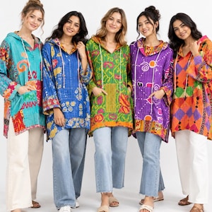 May include: Five long-sleeve hooded tunics featuring vibrant patchwork patterns in turquoise, blue, green, purple, and orange. Each pullover includes a front kangaroo pocket, a drawstring hood, and side slits, worn with light-colored denim jeans.