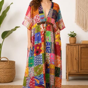 May include: A floor-length patchwork dress featuring a vibrant array of multicolored fabric squares with diverse floral, geometric, and abstract patterns. The garment has a deep V-neckline, short wide sleeves, and two side pockets in a loose fit.