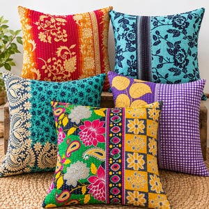 May include: Five square throw pillows featuring kantha stitching and diverse patterns. The collection includes red and orange floral, blue and black floral, teal paisley, purple with yellow leaves and gingham, and a multi-colored floral and geometric design.