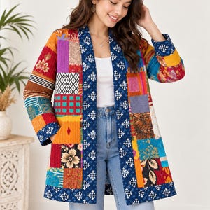 Könnte beinhalten: Eine langärmelige Steppjacke mit einem lebendigen Patchwork-Design, das verschiedene florale, geometrische und abstrakte Muster in Blau-, Orange-, Rot- und Gelbtönen aufweist. Die Jacke hat eine dunkelblaue Kante mit einem weißen, sich wiederholenden Sternmotiv.