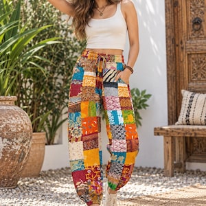 Peut inclure: Pantalon taille haute avec un motif patchwork coloré composé de divers imprimés floraux et géométriques dans des tons jaune, rouge, bleu et orange. Le pantalon possède une taille élastique avec un cordon de serrage et des chevilles resserrées.