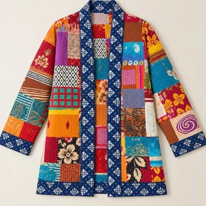 Pode incluir: Um casaco acolchoado com um design de patchwork vibrante, apresentando vários padrões florais, geométricos e paisley em tons de vermelho, amarelo, azul e laranja. A peça tem um acabamento azul escuro com um motivo de estrela branco.