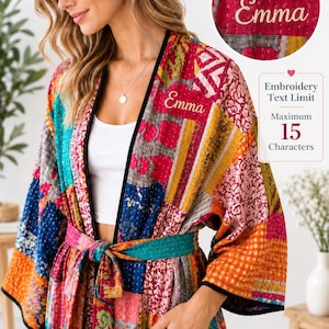 Puede incluir: Una bata tipo kimono de patchwork multicolor con una variedad de patrones florales y geométricos en tonos rojos, azules, naranjas y amarillos. La bata incluye un borde negro, un cinturón a juego y el nombre Emma bordado en el pecho.