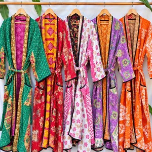 May include: Five long-sleeved robes hanging on wooden hangers, each featuring distinct vibrant patterns and colors including green, red, white, purple, and orange. The robes have black trim along the front edges, cuffs, and pockets.