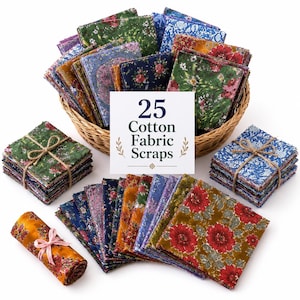 Op de afbeelding: Een collectie van 25 katoenen stofresten met diverse bloemmotieven in tinten groen, blauw, rood en goud. De set bevat een gevlochten mand gevuld met gevouwen vierkanten, twee stapels gebonden met touw en één opgerold stuk met een roze lint.