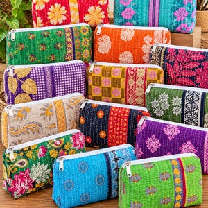 May include: A collection of rectangular zipped pouches made from quilted fabric in various vibrant colours and patterns, including floral, paisley, and geometric prints. Each pouch features a white zip closure and visible running stitch details.