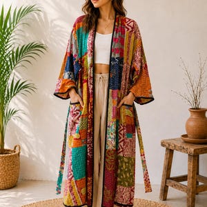 May include: A long, open-front kimono robe featuring a vibrant patchwork design with various colorful fabric squares in shades of red, orange, yellow, green, and blue. The garment includes long sleeves, two front pockets, and black trim.