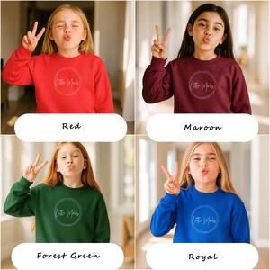 以下が含まれることがあります： 赤、マルーン、フォレストグリーン、ロイヤルブルーの4色のスウェットシャツが表示されています。各スウェットシャツには、「Little Mocks」というテキストが入った白い円形のロゴが付いています。モデルはピースサインをしています。