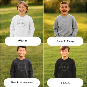 Peut inclure: Quatre sweat-shirts pour enfants, blancs, gris sport, gris fonc&eacute; et noirs. Chaque sweat-shirt pr&eacute;sente un logo circulaire avec le texte "Little Marks" dans un style manuscrit. Les sweat-shirts sont pr&eacute;sent&eacute;s sur un fond herbeux vert.