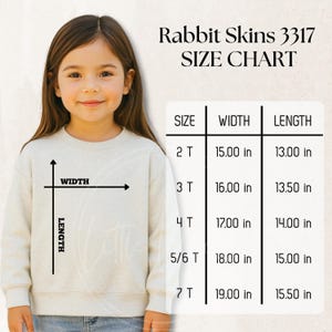 以下が含まれることがあります： 明るい色のスウェットシャツを着た若い女の子。画像には、「Rabbit Skins 3317」とラベル付けされたサイズチャートが含まれており、幅と長さのインチ単位の測定値が記載されています。サイズは2Tから7Tまであります。