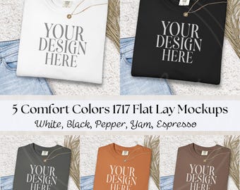 May include: Five Comfort Colors 1717 flat lay mockups in white, black, pepper, yam, and espresso. Each shirt displays the text "YOUR DESIGN HERE". The shirts are folded and placed on denim jeans.