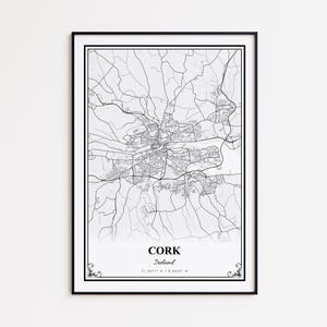 May include: A framed monochrome map print of Cork, Ireland. The detailed map shows the city's roads and rivers. The city name and coordinates are printed in a white box at the bottom. The print is enclosed in a black frame.