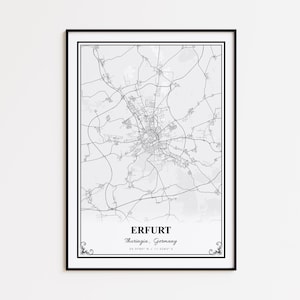 May include: A framed black and white map print of Erfurt, Germany. The map shows the city's road network and is labeled with the city name, region, and coordinates. The print has a black border and decorative corner elements.