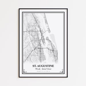 May include: A framed monochrome map print of St. Augustine, Florida, showing the city's layout and geographical details. The print includes the city name and coordinates, set within a black frame.