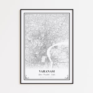 May include: A framed black and white map print of Varanasi, Uttar Pradesh, India. The map details the city's layout with streets and landmarks. The city name and coordinates are printed at the bottom. The frame is black.