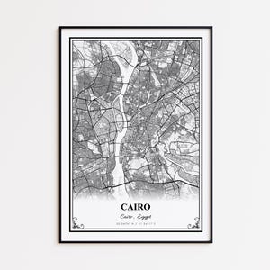 May include: Black and white framed map print of Cairo, Egypt. The detailed map shows the city's layout, with the name "Cairo" and coordinates at the bottom. The print has a decorative border.
