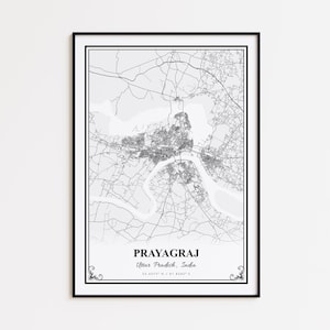 May include: A framed black and white map print of Prayagraj, Uttar Pradesh, India. The map shows the city's layout with roads, rivers, and urban areas. The city name and coordinates are printed at the bottom.