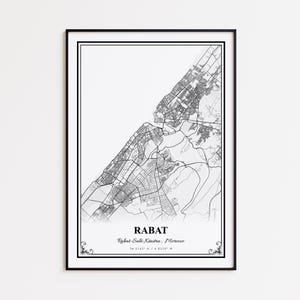 Può includere: Una stampa incorniciata in bianco e nero della mappa di Rabat, Marocco. La mappa mostra la disposizione della città con strade e punti di riferimento. Il nome della città e le coordinate sono stampati in basso. La stampa è racchiusa in una cornice nera.