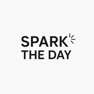 May include: Black text on a white background reads "SPARK THE DAY". The word "SPARK" has a small graphic of radiating lines coming from the letter "K". The text is centered and in a bold, sans-serif font.
