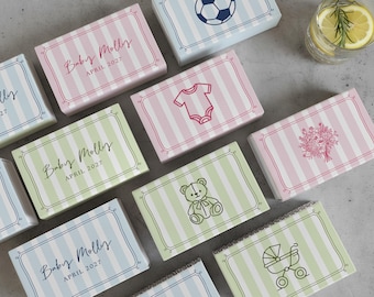 May include: Various rectangular gift boxes with pastel striped patterns. Some boxes feature baby-themed illustrations, including a onesie, teddy bear, and a pram. Others have the text "Baby Molly April 2027".