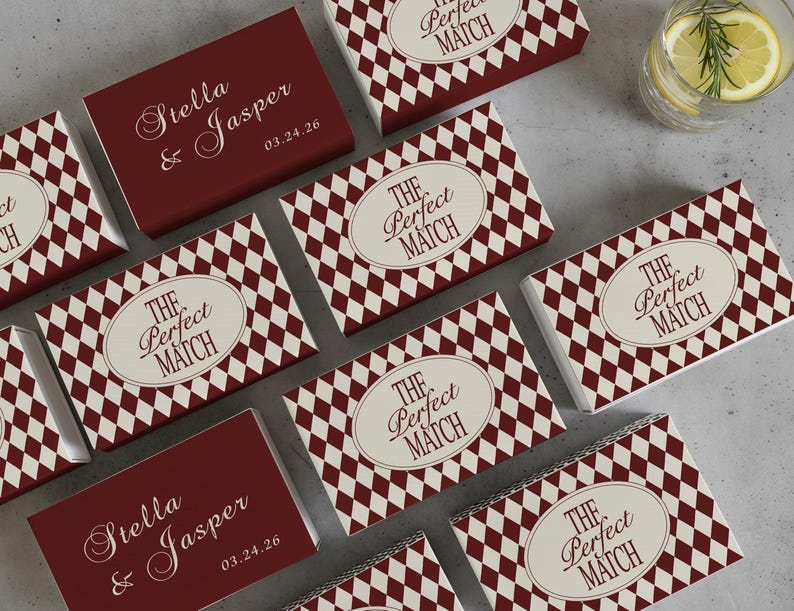May include: A collection of matchboxes with a burgundy and cream diamond pattern. Some boxes feature the text "The Perfect Match" in an oval, while others display "Stella & Jasper" and a date. A refreshing drink is in the background.