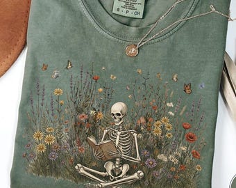 Camiseta Comfort Colors con diseño de esqueleto leyendo un libro, con estampado botánico de flores silvestres, estilo cottagecore, dark academia y estilo vintage.