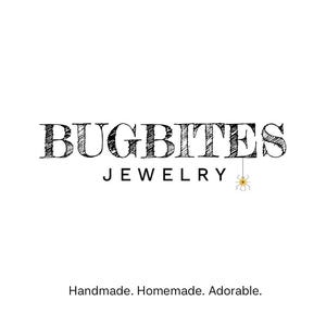 May include: The logo for BugBites Jewelry, featuring the brand name in a textured, black font. Below, the word "JEWELRY" is in a smaller, black font. A small, yellow spider graphic hangs from the letter "Y". The text "Handmade. Homemade. Adorable." is below.
