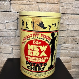 May include: Vintage yellow metal potato chips tin with black silhouette figures and text. The tin reads "The New Era Scientifically Processed Potato Chips" and "A Healthy Food on the Alkaline Side". The tin is approximately 7 inches tall.