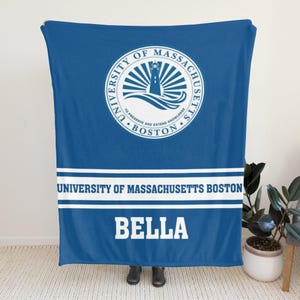 Könnte beinhalten: Eine blaue Decke mit dem Siegel der University of Massachusetts Boston und Text. Das Siegel zeigt einen Leuchtturm und die Worte "University of Massachusetts Boston" und "To Preserve and Extend Knowledge". Der Name "BELLA" wird in weißen Blockbuchstaben angezeigt.