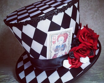May include: A black and white checkered top hat with a black ribbon and a card featuring the Queen of Hearts from Alice in Wonderland. The hat is decorated with red roses.