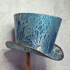 May include: A blue and gold top hat with a peacock feather design. The hat has a wide brim and a tall crown.