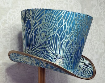 May include: A blue and gold top hat with a peacock feather design. The hat has a wide brim and a tall crown.