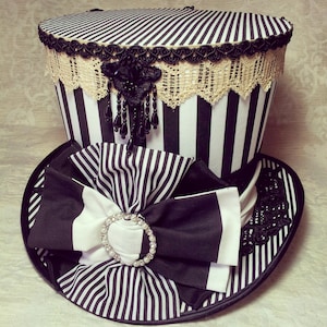 May include: A black and white striped top hat with a black and white striped bow and a black and white lace trim.