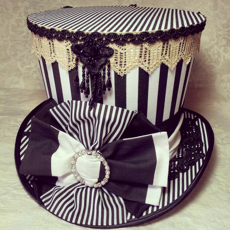 May include: A black and white striped top hat with a black and white striped bow and a black and white lace trim.